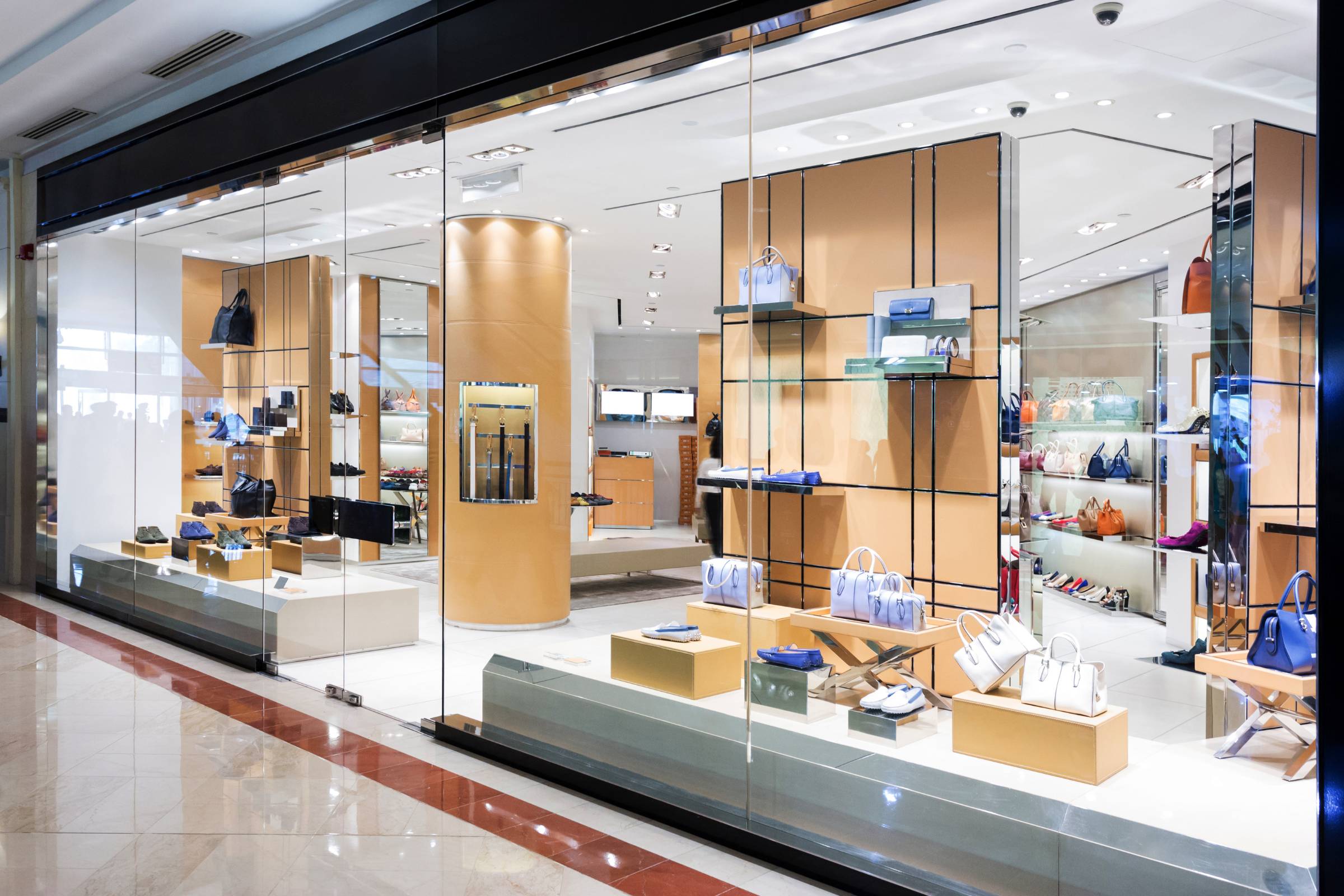 A modern retail store with glass walls displaying handbags, shoes, and accessories on shelves in a brightly lit interior—perfectly finished with expert new construction painting for a flawless, contemporary look.
