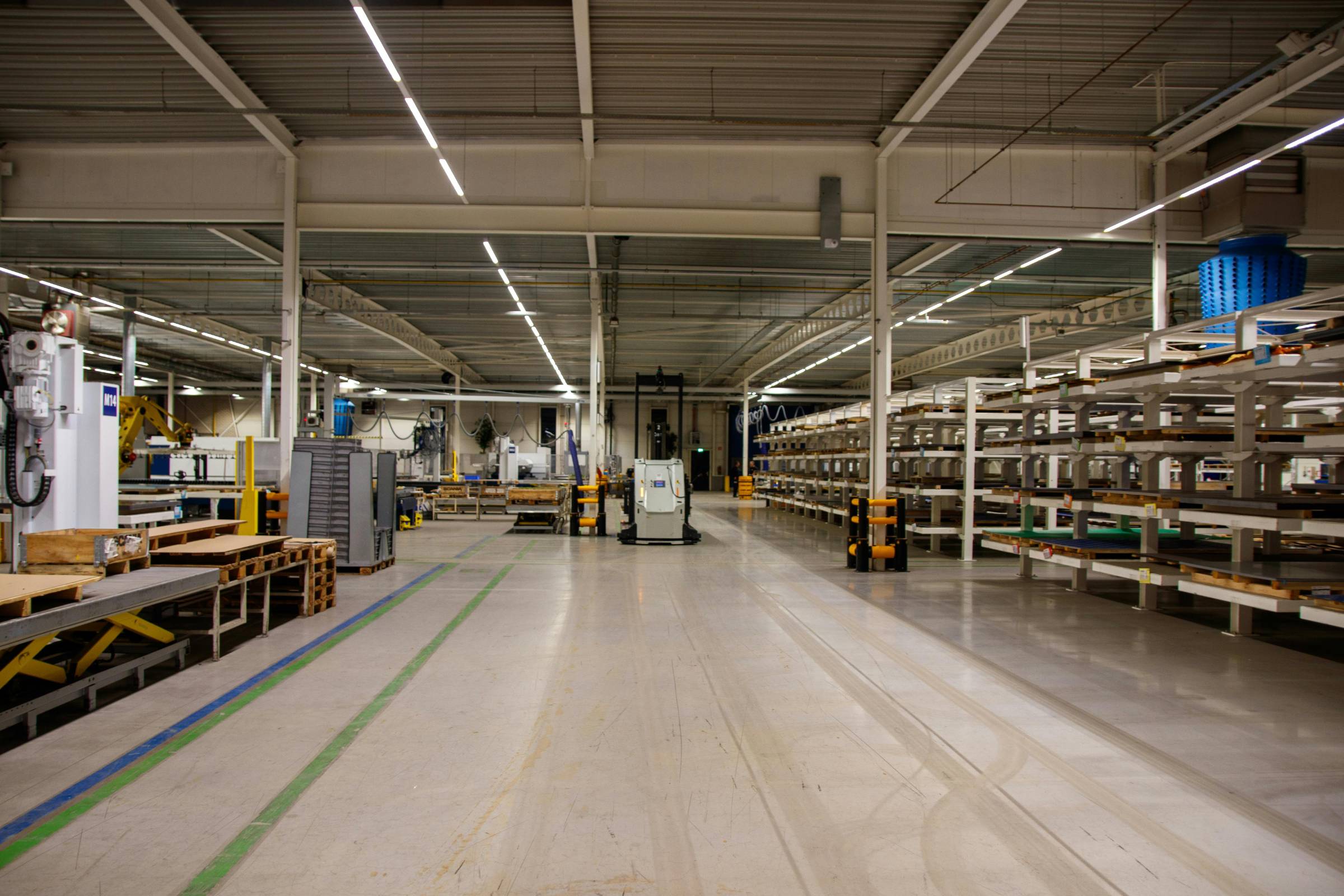 Spacious, well-lit factory floor with organized shelving units, pallets, industrial equipment, and empty walkways—ideal for efficient workflows and perfect for New Construction Painting projects.